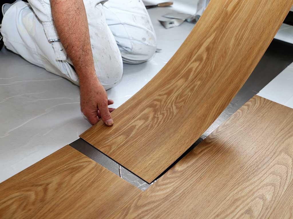 Construction worker installing vinyl flooring